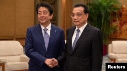 Kineski premijer Li Kećijang i japanski premijer Šinzo Abe rukuju se tokom sastanka u Velikoj dvoarani naroda u Pekingu, 25. oktobra 2018.