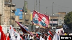 Iraqis, including supporters of Hashid Shaabi (Popular Mobilization Forces), hold flags and placards depicting senior Iranian military commander General Qassem Soleimani and Iraqi militia commander Abu Mahdi al-Muhandis, in Baghdad, Jan. 3, 2021.