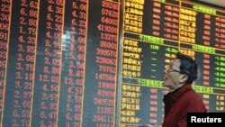 An investor looks at an electronic board showing stock information at a brokerage house in Hangzhou, Zhejiang province, China, December 14, 2012. 