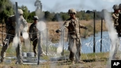 FILE - In this Nov. 16, 2018, photo, members of the U.S. military install multiple tiers of concertina wire along the banks of the Rio Grande near the Juarez-Lincoln Bridge at the U.S.-Mexico border in Laredo, Texas. 