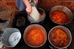 FILE - Chef Walter Ferreira pours rice into a stew at a soup kitchen in Luque, Paraguay, May 11, 2020. The number of soup kitchens in the country has increased, as the country's economy grinds down due to the new coronavirus pandemic lockdown.