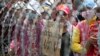 Cambodian garment workers shout slogans behind barbed wire set up by police near the Council of Ministers building during a rally in Phnom Penh, Cambodia, Monday, Dec. 30, 2013. The workers are demanding a raise in their monthly salary from US $160 to $80. (AP Photo/Heng Sinith)