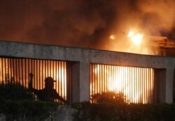 FILE - Student protesters throw stones to riot police as a toll gate burns during a protest outside the parliament in Jakarta, Indonesia, Sept. 24, 2019.