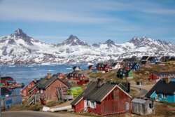 FILE - Snow-covered mountains rise above the harbor and town of Tasiilaq, Greenland, Jan. 10, 2019.