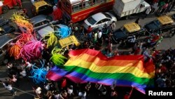 FILE - Participants holding a rainbow flag pass through a junction during a gay pride parade, which is promoting gay, lesbian, bisexual and transgender rights, in Mumbai, Jan. 31, 2015.