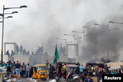 Demonstran berdiri di depan pasukan keamanan Irak di Jembatan Al Jumariyah selama protes atas korupsi, kurangnya pekerjaan, dan layanan yang buruk, di Baghdad, Irak 27 Oktober 2019. (Foto: Reuters/Khalid al-Mousily)