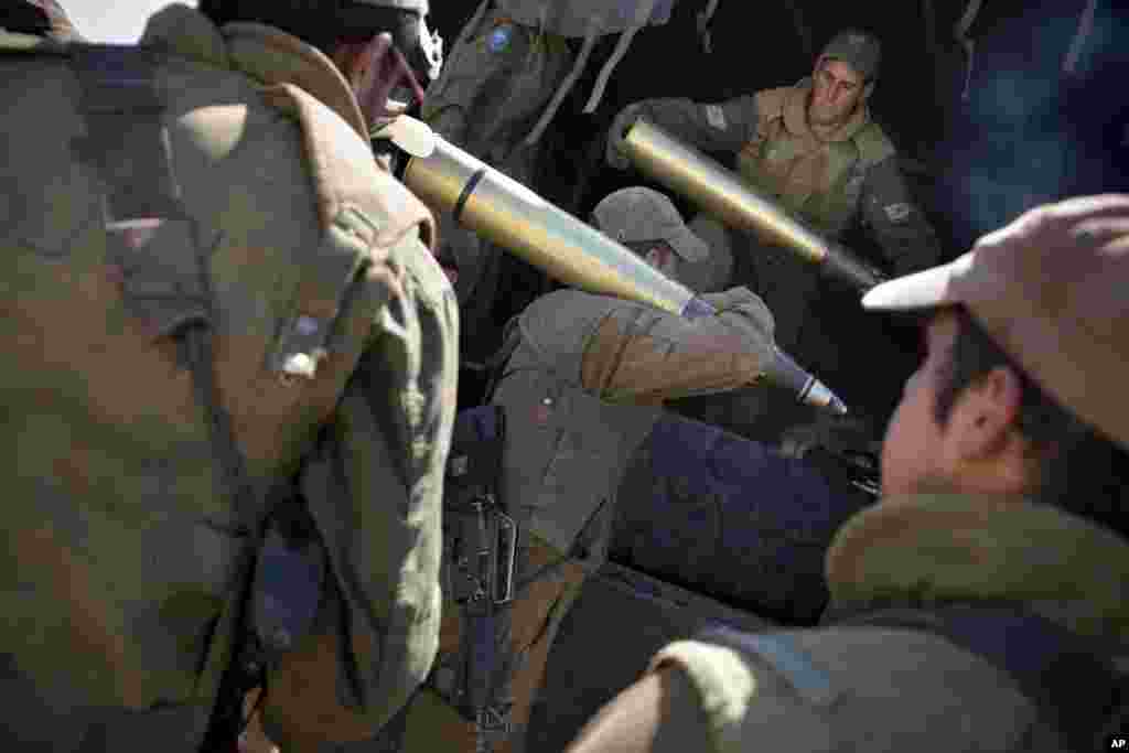 Israeli soldiers carry shells to their tank near Alonei Habashan on the Israeli occupied Golan Heights, close to the cease-fire line between Israel and Syria, June 22, 2014.