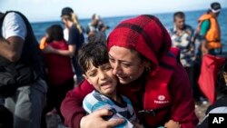 Une Syrienne porte un enfant qu'elle embrace à leur arrivée à l'ile Lesbos, Grèce, venant de la Turquie, 11 septembre 2015.