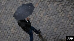 FILE - A man shelters under an umbrella as snow turns to sleet and rain in Berlin, Germany, May 7, 2021. 