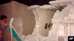 A local resident looks at his damaged house following a severe earthquake hit the area, in Harnai, about 100 kilometers from Quetta, Pakistan, Oct. 6, 2021. 
