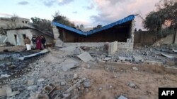 FILE - Libyans inspect a damaged building following a reported airstrike in the capital Tripoli's suburb of Tajoura, Dec.29, 2019.