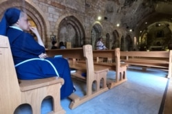 FILE - A nun looks on as people visit the Monastery of Saint Anthony of Qozhaya in the heart of the Qadisha valley, in Zgharta district, Lebanon, June 23, 2019.