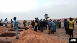 Officials and residents stand near freshly dug graves, June 11, 2019 in the Dogon village of Sobane-Kou, near Sangha, after an attack that killed over 100 ethnic Dogon on June 9, 2019.