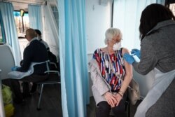 A woman receives a dose of the Oxford-AstraZeneca COVID-19 vaccine inside a mobile vaccination center for the COVID-19, in Thamesmead, London, Feb. 14, 2021.
