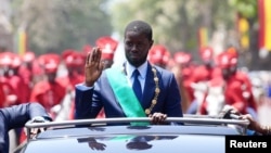 Senegalese President Bassirou Diomaye Faye waves to supporters from a car after taking the oath of office as president during his inauguration ceremony near Dakar on April 2, 2024.