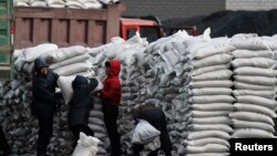 지난해 1월 북한 접경도시 신의주에서 주민들에게 밀가루 포대를 나눠주고 있다. 압록강 건너 중국 단둥에서 바라본 모습. (자료사진)