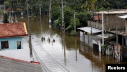 A group of men walk through a flooded road during a rescue mission in Nagoda village in Kalutara, Sri Lanka, May 29, 2017. 