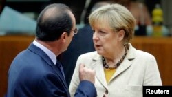 FILE - Germany's Chancellor Angela Merkel (R) and France's President Francois Hollande arrive for a working session during an EU summit in Brussels, Oct. 24, 2014. 