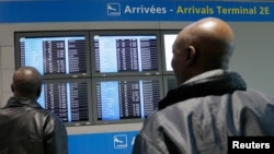 Des hommes regardent un écran à l'aéroport international Charles de Gaulle à Roissy, près de Paris, le 18 octobre 2014. ( REUTERS/Gonzalo Fuentes)