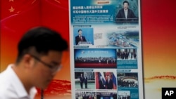 រូបឯកសារ៖ បុរស​ម្នាក់​ដើរ​ក្បែរ​ផ្ទាំង​ប៉ាណូ​រដ្ឋាភិបាល​ដែល​ផ្សព្វផ្សាយ​អំពី​គំនិត​ផ្តួចផ្តើម​ផ្លូវ​ខ្សែក្រវាត់​របស់​ប្រធានាធិបតីចិន​លោក Xi Jinping នៅ​ខាងក្រៅ​ស្ថានីយ៍​រថភ្លើង​ក្រោមដី​ក្នុង​ទីក្រុង​ប៉េកាំង ប្រទេសចិន កាលពី​ថ្ងៃទី២៨ ខែសីហា ឆ្នាំ២០១៨។