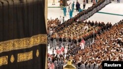 Workers arrive with a police escort to replace the Kiswa (silk cloth covering the Kaaba) at the Grand Mosque in Mecca, Saudi Arabia, July 6, 2024. S(audi Press Agency/Handout)