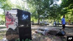 FILE - An unidentified man walks past a toppled statue of Charles Linn, a city founder who was in the Confederate Navy, in Birmingham, Ala., June 1, 2020.