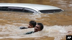 People swim through a flooded neighborhood following heavy rains in Jakarta, Indonesia, Feb. 20, 2021.