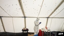 A medical worker wearing a protective suit waits for the next patient at a drive-in coronavirus testing center in Prague, Czech Republic, Oct. 14, 2020.