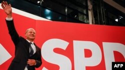 German Finance Minister, vice-chancellor and the Social Democrats (SPD) candidate for Chancellor Olaf Scholz waves on the stage after the estimates were broadcast on TV, in Berlin, Sept. 26, 2021.