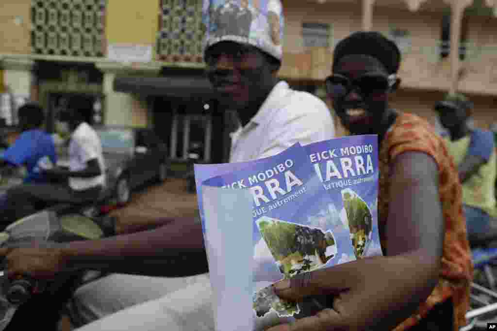 Supporters of presidential candidate Cheick Modibo Diarra distribute campaign flyers from the back of a moped as they ride in a campaign caravan through the streets of Bamako, Mali, July 20, 2013.