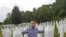 Behidin Piric, a survivor of the Srebrenica Genocide of 1995, stands next to the graves of his grandfather and great-uncles, who were killed in the massacre,while visiting the Srebrenica Memorial Center in Bosnia in 2019. 