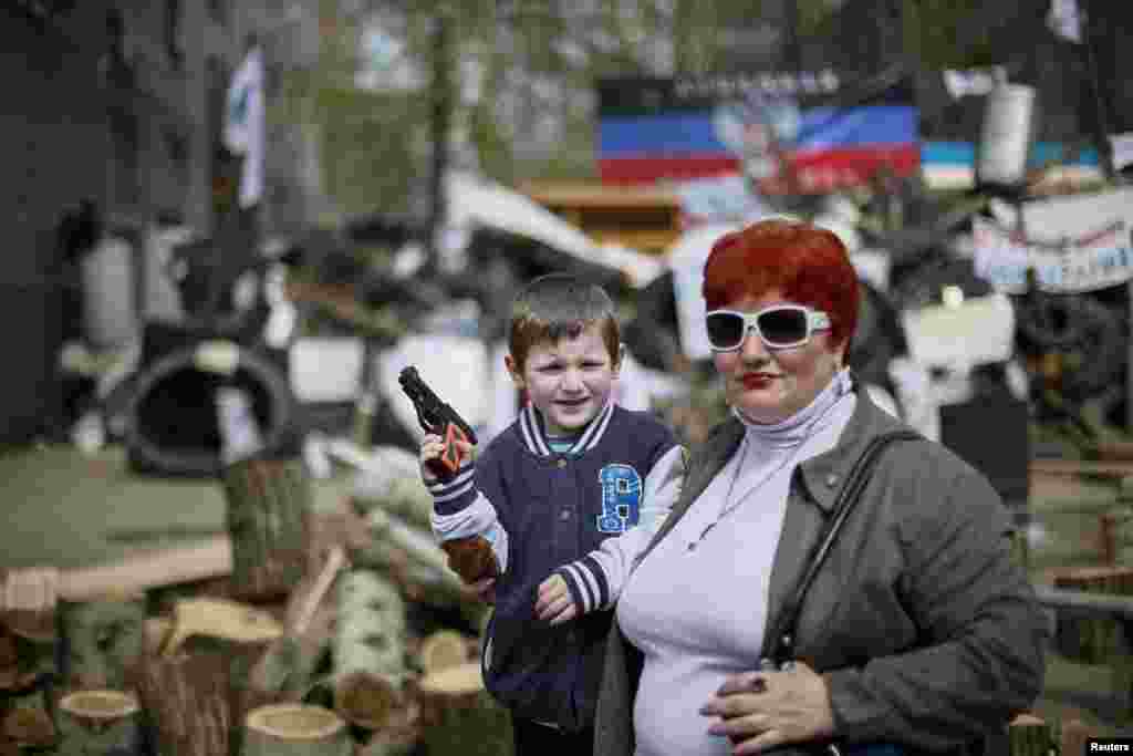 A boy with a toy gun poses for a picture in front of barricades at the police headquarters in the eastern Ukrainian town of Slaviansk.