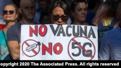 FILE - Demonstrators attend a protest against nationwide restrictions against COVID-19 in Madrid, Spain, Aug. 16, 2020. A banner reads in Spanish 'No vaccine No 5G No mask'.