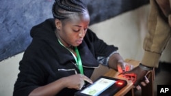 An offical from the electoral commmision registers voters through a fingerprint scan machine at the Panarae Primary School in Kajiado, Kenya, Aug. 8, 2017. 