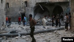 FILE - People inspect a site hit by what activists said was an airstrike by forces loyal to Syria's President Bashar al-Assad, in Qadi Askar district in Aleppo, Syria, July 21, 2014.