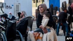 Seorang wanita menggendong bayi saat menunggu untuk berangkat bersama konvoi Organisasi Kesehatan Dunia dan Bulan Sabit Merah Palestina di Khan Yunis, selatan Gaza, mengevakuasi pasien dan korban perang dari daerah tersebut pada 6 November 2024.