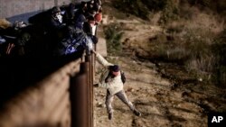 Seorang migran melompat dari pagar perbatasan AS-Meksiko untuk masuk ke wilayah AS di dekat Tijuana, Meksiko, 1 Januari 2019 lalu. 