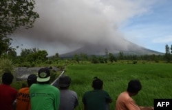 Penduduk menyaksikan gunung berapi Mayon memuntahkan abu di tempat wisata dekat reruntuhan Cagsawa di Daraga di Provinsi Albay, selatan Manila (Foto: AFP)