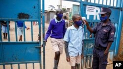 Schoolchildren have their temperature taken as they arrive at the Olympic Primary School in Kibera, one of the capital Nairobi's poorest areas in Kenya, Oct. 12, 2020.
