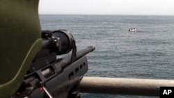 FILE - A Turkish commando, left, points his rifle toward five pirates surrounded in the Gulf of Aden, off the coast of Somalia, July 24, 2009.