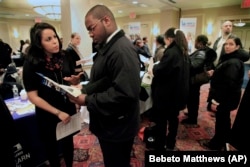 Daniela Silvero, left, an admissions officer at ASA College, discusses job opportunities with Patrick Rosarie, who is seeking a job in IT, during JobEXPO's 2012 job fair in New York.