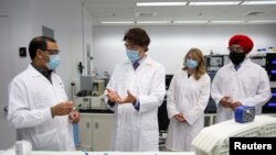 Perdana Menteri Kanada Justin Trudeau didampingi Menteri Pembangunan Ekonomi Melanie Joly (kedua dari kanan) dan Menteri Inovasi, Sains, dan Industri Navdeep Bains (kanan) meninjau pembuatan vaksin di Dewan Riset Nasional, di Montreal, Quebec, Kanada, Sen