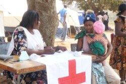 While getting airtime to call relatives, Gladys Majawa says she still doesn't know where her children's father is as both ran in different directions while fleeing xenophobic attacks. (VOA/L. Masina)