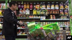  A man pushes a shopping cart past a display of nuts imported from the United States and other countries at a supermarket in Beijing, Monday, April 2, 2018. (AP Photo/Andy Wong) 