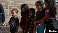 Anak-anak berdiri dalam antrian sebagai keluarga imigran yang memiliki dokumen dilepaskan dari fasilitas penahanan di sebuah halte bus di McAllen, Texas, AS, 22 Juni 2018 (foto: Reuters/Loren Elliott)