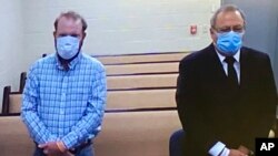 In this image made from video, Travis McMichael, left, and Greg McMichael listen to a preliminary hearing via a court video feed June 4, 2020, while inside the Glynn County jail in Brunswick, Ga. 
