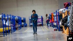 A migrant walks between rows of bunk beds at a government run shelter in Ciudad Juarez, Mexico, Dec. 18, 2022. 