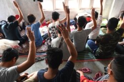 Myanmarese policemen, who fled Myanmar and crossed illegally to India, hold the three-finger salute in a temporary shelter at an undisclosed location in India's northeastern state of Mizoram on March 13, 2021. - Scores of Myanmar policemen and their famil