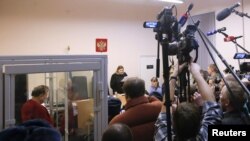 Russian historian and professor Oleg Sokolov, who is accused of murdering his girl friend and former student, stands inside a defendants' cage during a court hearing in Saint Petersburg, Russia, Nov. 11, 2019. 