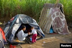 FILE - A Roma woman sits next to her tent in a camp on the outskirts of Rome, July 21, 2008.